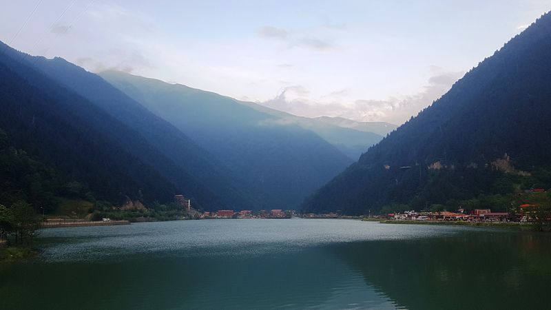 Uzungöl'ün iki yamaç arasına sıkışmış su aynası ve arkasında sıradağlar.
