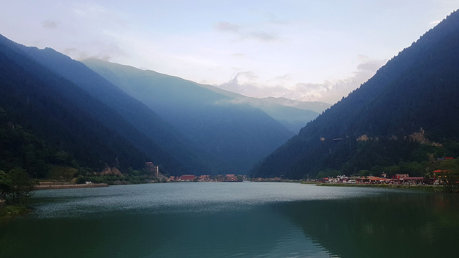Uzungöl'ün iki yamaç arasına sıkışmış su aynası ve arkasında sıradağlar.