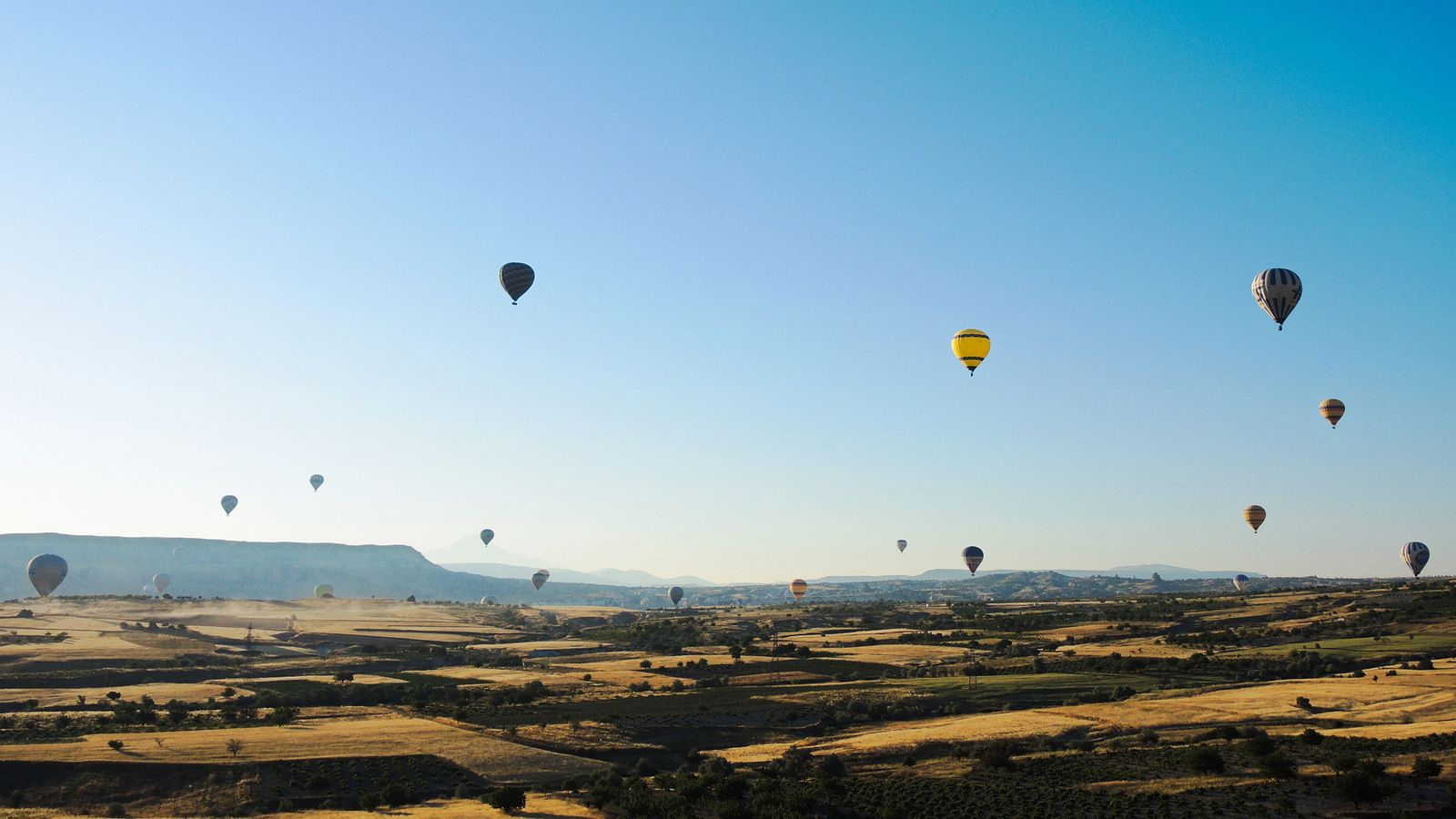 Sabah saatlerinde Kapadokya vadileri üzerinde yükselen sıcak hava balonları.