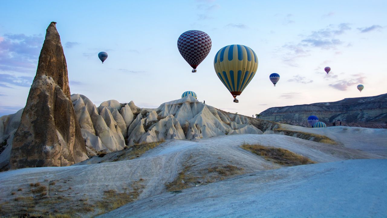 Kapadokya’nın peri bacaları üzerinde gün doğumunda süzülen sıcak hava balonları.