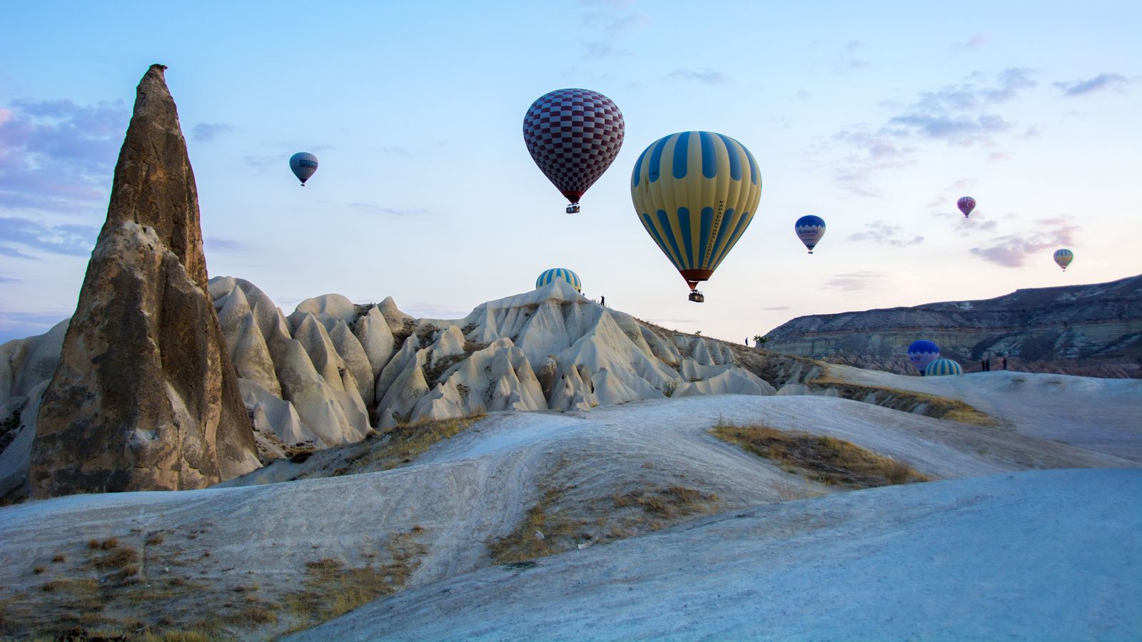 Kapadokya’nın peri bacaları üzerinde gün doğumunda süzülen sıcak hava balonları.